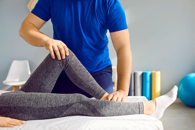 a chiropractor treating a patient's knee a chiropractor treating a patient's knee